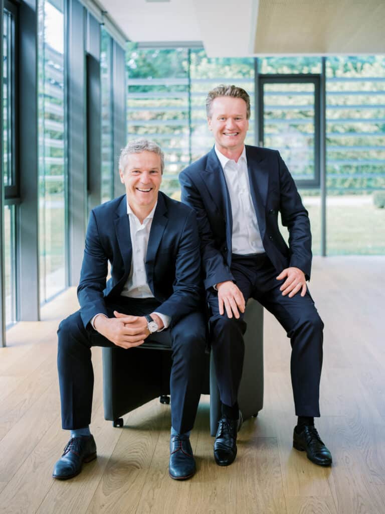 Die beiden Eigentümer Christian und Georg Knill sitzen beide auf einem Stuhl